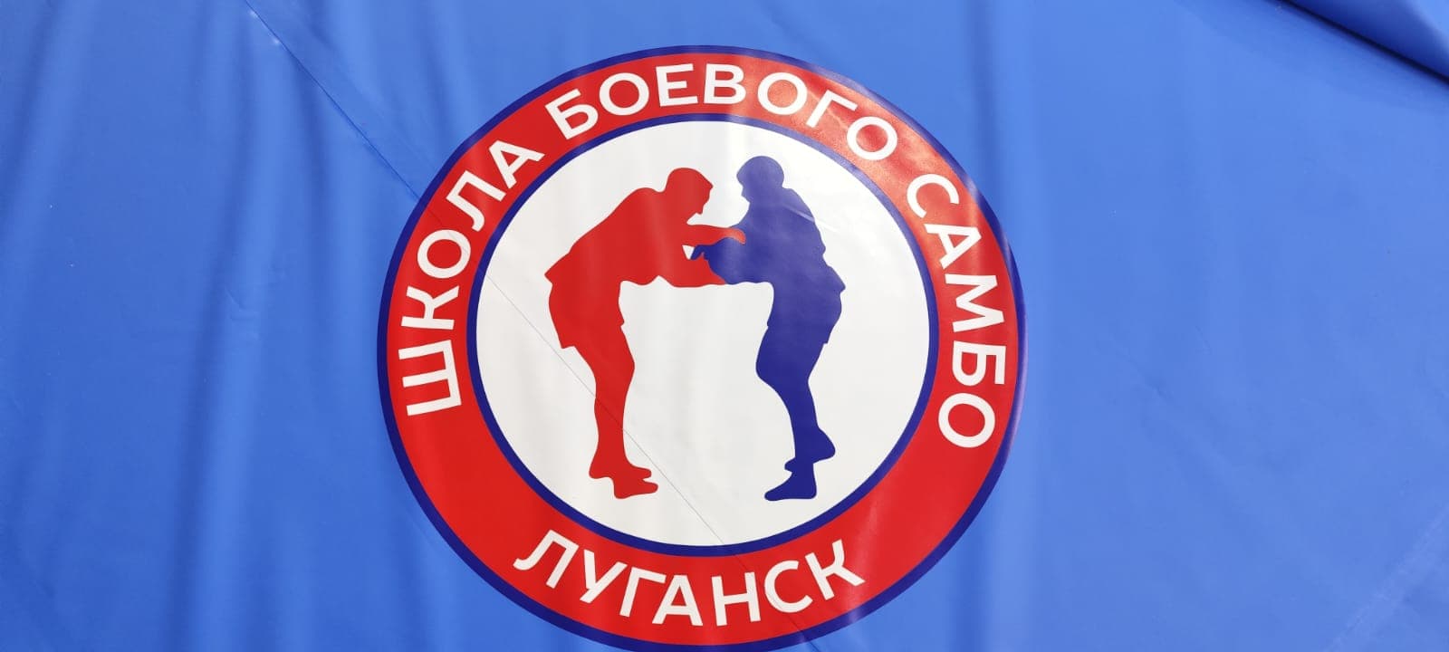 Зал школы самбо в Луганске с покрытием и логотипом на ковре